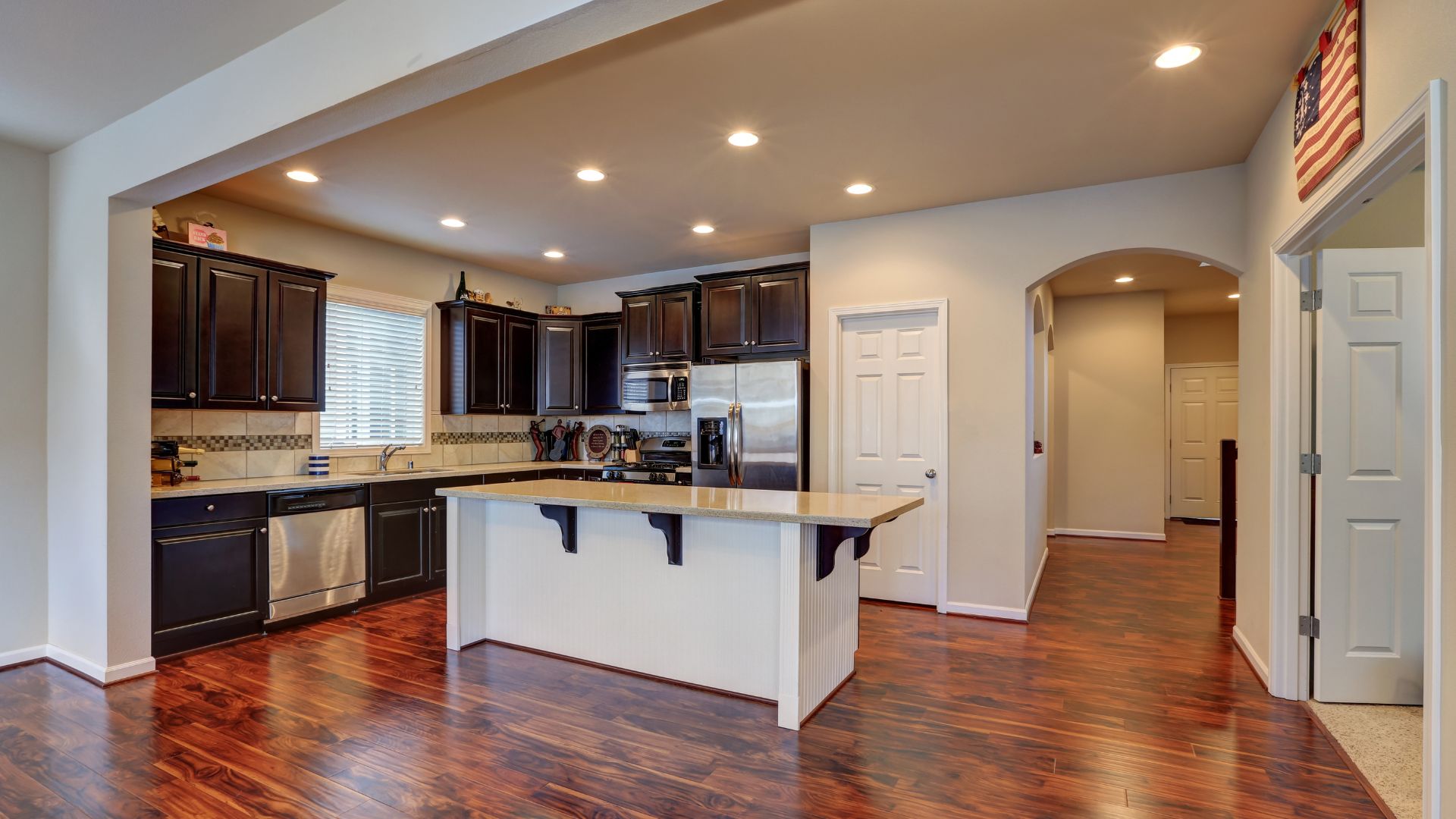 Modern kitchen with dark cabinets, white island, and hardwood floors