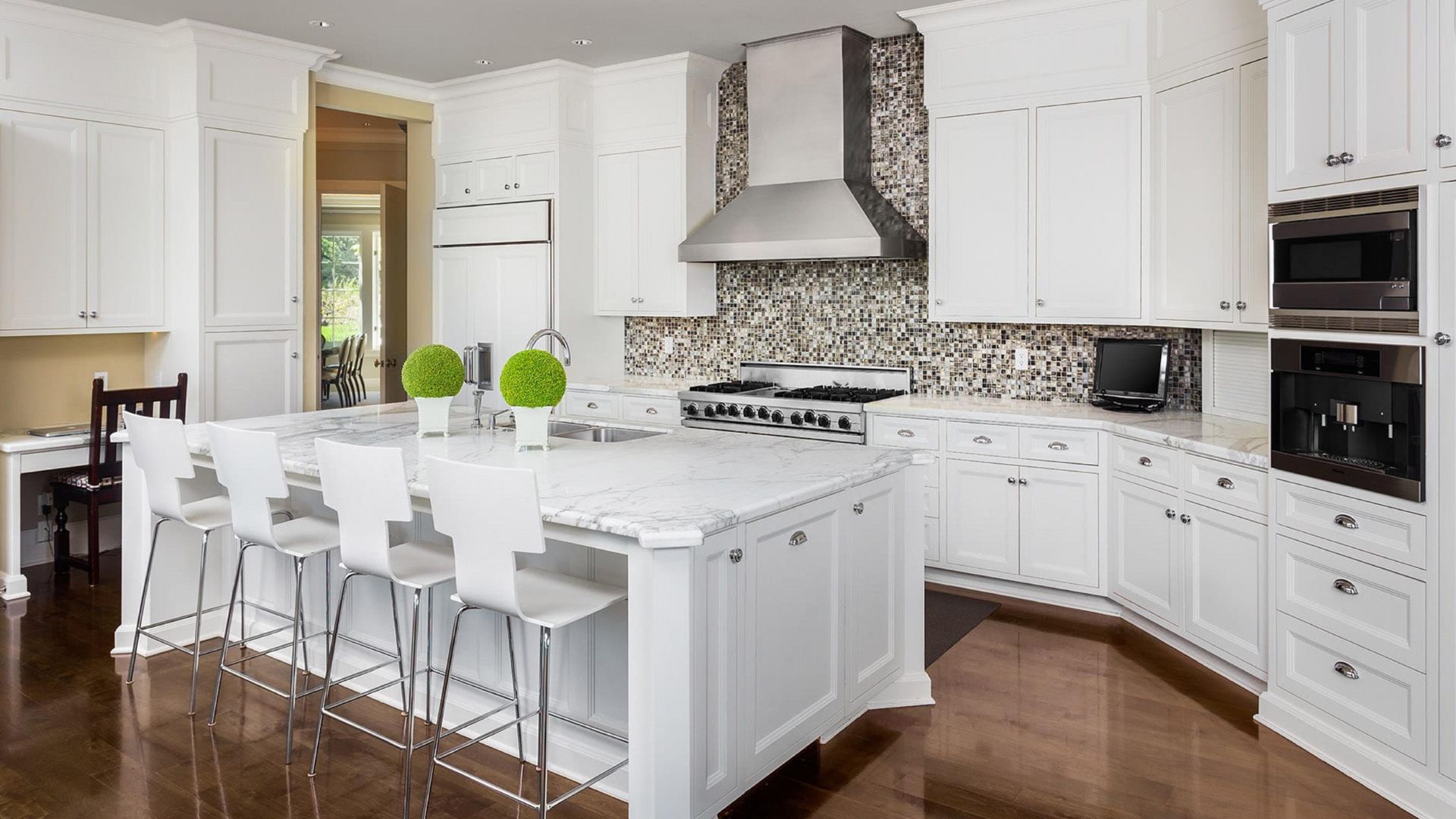 Modern white kitchen with marble island, mosaic backsplash, and green decor