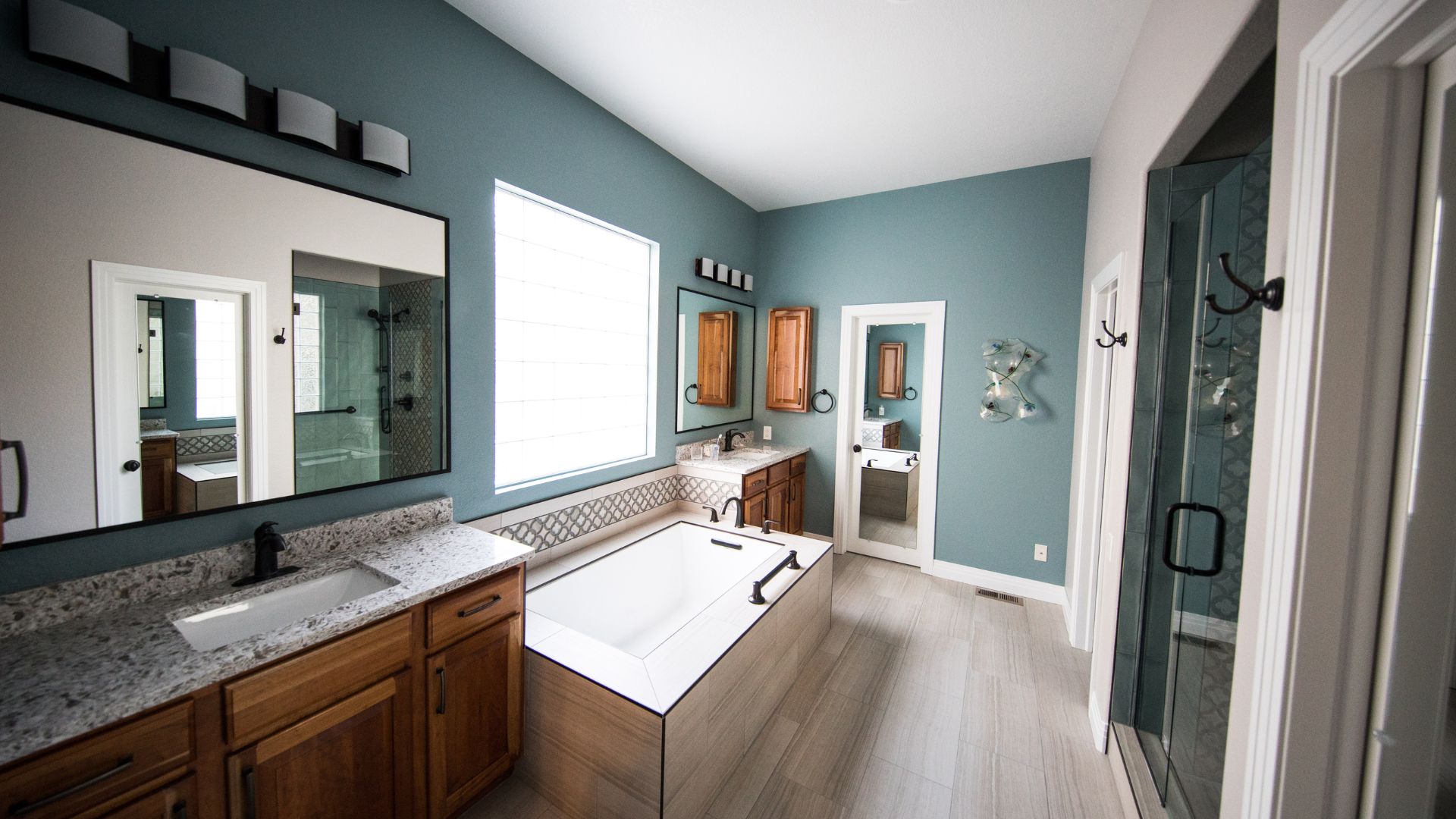 Modern bathroom with blue walls, wooden cabinets, and large white bathtub
